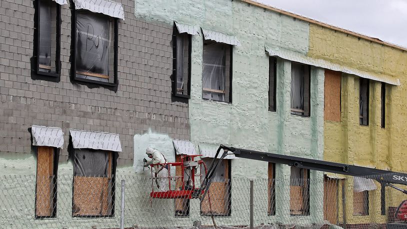 Construction workers in hard hats and safety gear, engaged in a discussion on a job site.